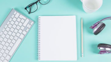 Um caderno de desenhos em branco aberto com vários objetos ao redor
